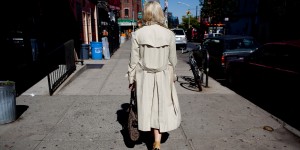 Woman in beige trenchcoat walking down Bedford Ave in Williamsburg.